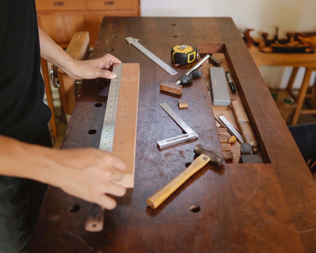 Hands measuring a sample on a workshop bench