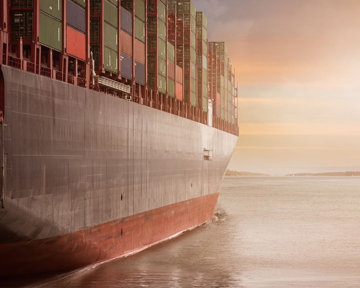 A loaded container ship approaching a terminal at dawn